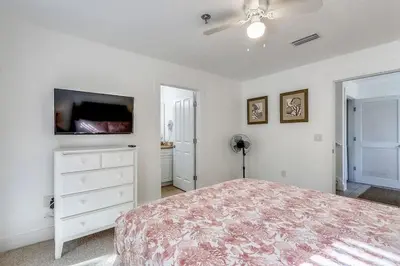 a white bedroom with a bed and a tv at Sunny Side Up by Book That Condo in Panama City Beach