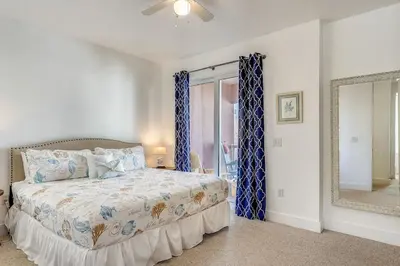 a bedroom with a bed with blue curtains and a mirror at Sunny Side Up by Book That Condo in Panama City Beach