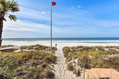 a path to the beach with a red flag at Sunny Side Up by Book That Condo in Panama City Beach