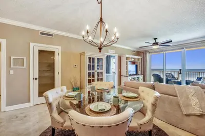 a dining room with a table and a couch at Tropic Winds Condominium #1405 by Book That Condo in Panama City Beach