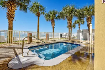 a swimming pool with palm trees and a fence at Tropic Winds Condominium #1405 by Book That Condo in Panama City Beach