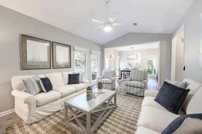a living room with white couches and a table at A Wave From It All in Santa Rosa Beach