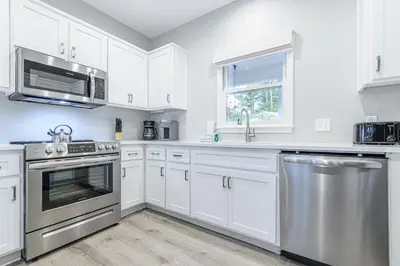 a kitchen with white cabinets and stainless steel appliances at A Wave From It All in Santa Rosa Beach
