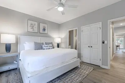 a white bedroom with a bed and a ceiling fan at A Wave From It All in Santa Rosa Beach
