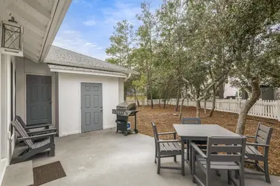 a patio with a table and chairs and a grill at A Wave From It All in Santa Rosa Beach