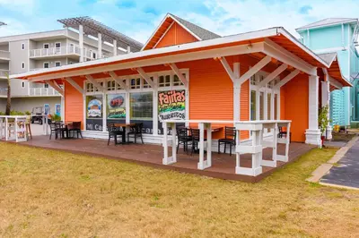 an orange restaurant with tables and chairs on a deck at A Wave From It All in Santa Rosa Beach