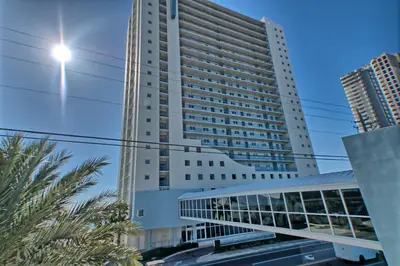 a tall white building with palm trees in front of it at Sterling Breeze - Luxury Beach Front Condo in Panama City Beach
