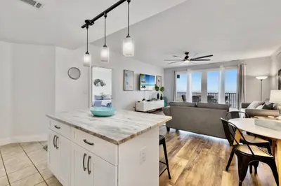 a kitchen and living room with a table and a couch at Luxurious 4 Bedroom Condo! Gulf Views! Sleeps 10 & Easy Beach Access! by Dolce Vita Getaways PCB in Panama City Beach