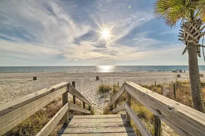 a wooden pathway to the beach with a palm tree at The Sage PCB Family Getaway - Walk to Beach! in Panama City Beach
