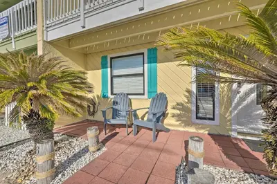 a patio with two chairs and a palm tree in front of a house at The Sage PCB Family Getaway - Walk to Beach! in Panama City Beach
