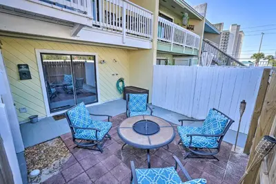a patio with a table and chairs and a fence at The Sage PCB Family Getaway - Walk to Beach! in Panama City Beach