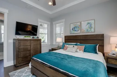 a bedroom with a large bed and a flat screen tv at Last Call at NatureWalk 30A in Seagrove Beach