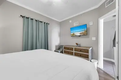 a white bedroom with a bed and a dresser at Seychelles 308 in Panama City Beach