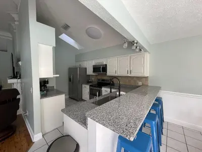 a kitchen with white cabinets and a counter with blue stools at A Shore Thing by Sand Seeker Vacations in Panama City Beach