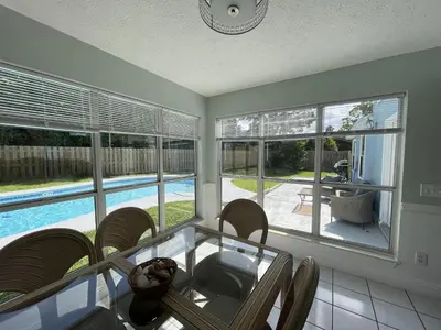 a dining room with a glass table and chairs and a pool at A Shore Thing by Sand Seeker Vacations in Panama City Beach