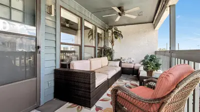 a porch with wicker chairs and a couch at Salt Life Loft by Sand Seeker Vacations in Panama City Beach