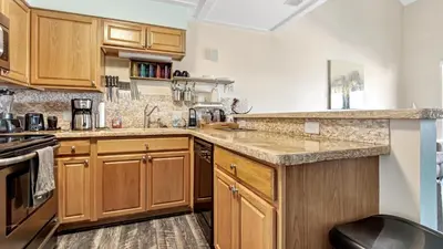 a kitchen with wooden cabinets and granite counter tops at Salt Life Loft by Sand Seeker Vacations in Panama City Beach