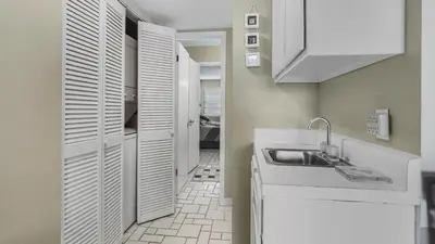 a small kitchen with white cabinets and a sink at Sweet Retreat by Sand Seeker Vacations in Panama City Beach