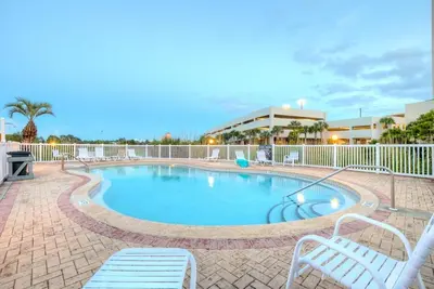 a swimming pool with two white chairs next to it at Sweet Retreat by Sand Seeker Vacations in Panama City Beach
