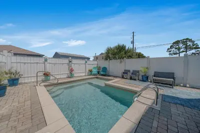 a swimming pool in a backyard with a fence at Deja Blue by Sand Seeker Vacations in Panama City Beach