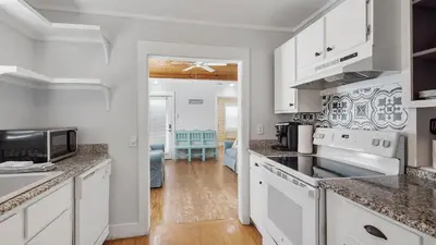 a kitchen with white cabinets and a living room at Laguna Shores by Sand Seeker Vacations in Panama City Beach