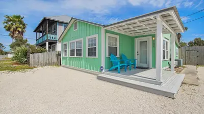 a green house with a blue chair on a porch at Laguna Shores by Sand Seeker Vacations in Panama City Beach