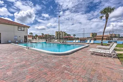 a swimming pool with two chairs and a palm tree at PCB Townhome Walk to Beaches, Resort Amenities! in Panama City Beach