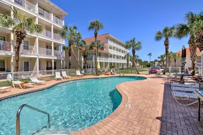 a swimming pool in front of a building with palm trees at PCB Townhome Walk to Beaches, Resort Amenities! in Panama City Beach