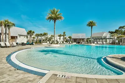 a swimming pool with palm trees in a resort at Prominence on 30A Rentals by Panhandle Getaways in Watersound Beach