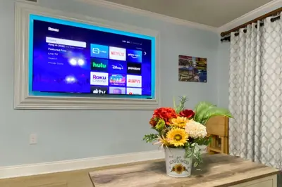 a vase of flowers on a table in front of a television at PCB Condo with Community Perks and Beach Access in Panama City Beach