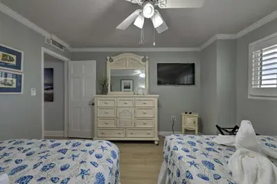 a bedroom with a bed and a dresser and a ceiling fan at PCB Condo with Community Perks and Beach Access in Panama City Beach