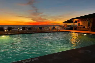 a swimming pool with a sunset in the background at PCB Condo with Community Perks and Beach Access in Panama City Beach