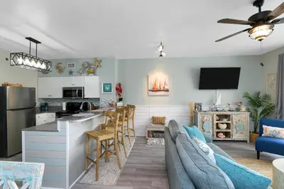 a living room with a couch and a kitchen at Shores of Panama 2024 in Panama City Beach