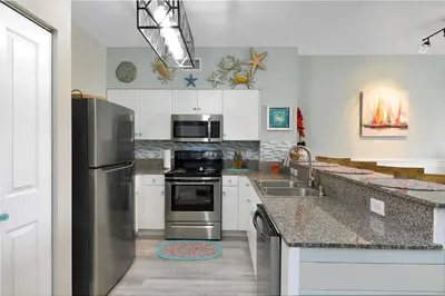 a kitchen with a stainless steel refrigerator and a sink at Shores of Panama 2024 in Panama City Beach