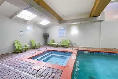 a swimming pool with green chairs and a table and a tablektop at Shores of Panama 2024 in Panama City Beach