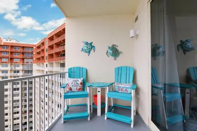 two blue chairs and a table on a balcony at Shores of Panama 2024 in Panama City Beach