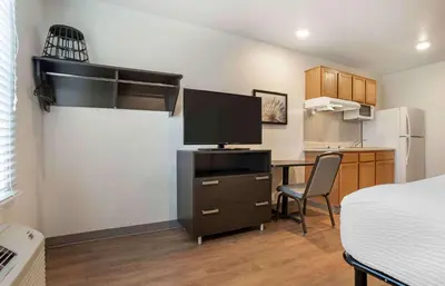 a room with a desk with a tv and a kitchen at Extended Stay America Select Suites - Panama City - Callaway in Callaway