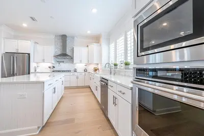 a kitchen with white cabinets and stainless steel appliances at Happily Eva After at Prominence 30A in Inlet Beach