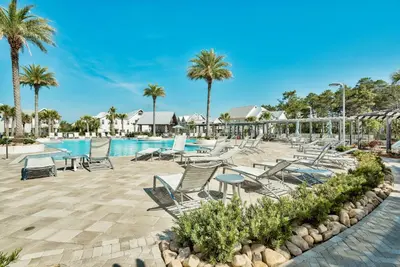 a pool at a resort with chairs and palm trees at Happily Eva After at Prominence 30A in Inlet Beach