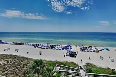 a beach with blue and white umbrellas and the ocean at Aqua 404 in Panama City Beach