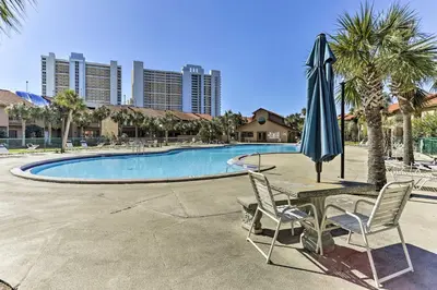 a table with an umbrella and chairs next to a pool at Walk to Beach PCB Condo with Oceanfront Pool Access in Panama City Beach