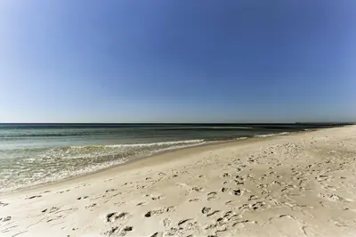 a beach with footprints in the sand and the ocean at Walk to Beach PCB Condo with Oceanfront Pool Access in Panama City Beach
