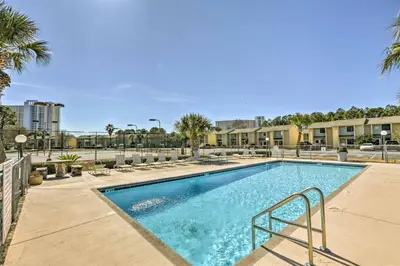 a swimming pool with palm trees and buildings at Walk to Beach PCB Condo with Oceanfront Pool Access in Panama City Beach
