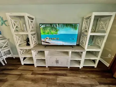 a television on a white entertainment center with shelves at Shores of Panama Resort, Direct Beachfront, 1 BR plus Bunks! by Dolce Vita Getaways PCB in Panama City Beach