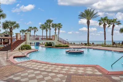 a large swimming pool with palm trees and a boat at Shores of Panama Resort, Direct Beachfront, 1 BR plus Bunks! by Dolce Vita Getaways PCB in Panama City Beach