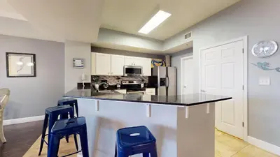 a kitchen with a counter and two blue stools at Tidewater 2608 in Panama City Beach
