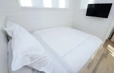 a bed with white sheets and a television in a room at Beautiful High End One Bed / 1 Bath Carriage House in Rosemary Beach