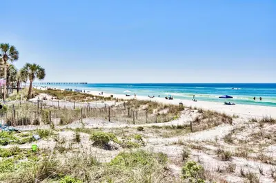 a beach with palm trees and people in the water at Beachside #8 - Beachfront - Sleeps 10! in Panama City Beach