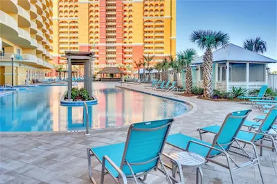 a swimming pool with blue chairs and a building at Calypso Resort Tower 3 by Panhandle Getaways in Panama City Beach