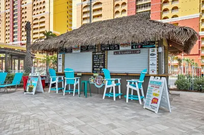 a bar with blue chairs and a straw roof at Calypso Resort Tower 3 by Panhandle Getaways in Panama City Beach